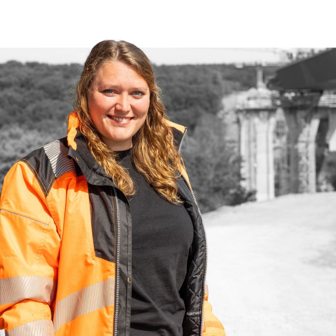 blonde 28-jährige Bauingenieurin steht mit  Warnweste vor eimer Brückenbaustelle